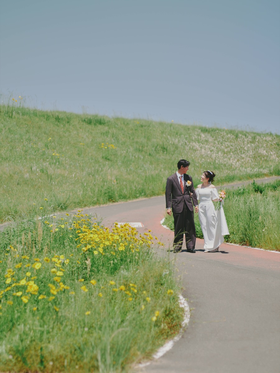 黄色い花の咲く道を歩くふたりの前撮り